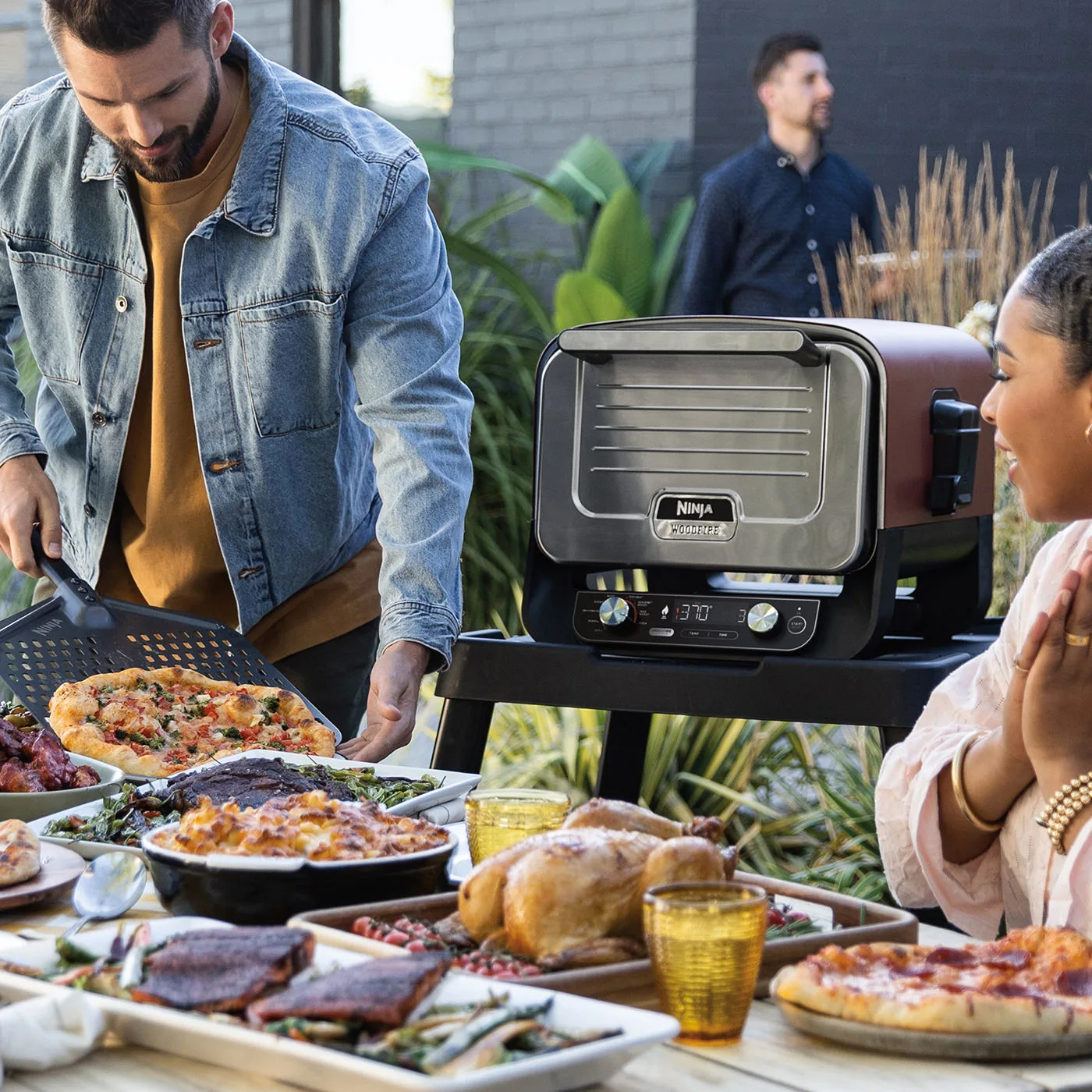 Ninja-OO101UK-InUse-Patio-OnStand-TableSet-Group-ServingPizza-2-RT_RGB